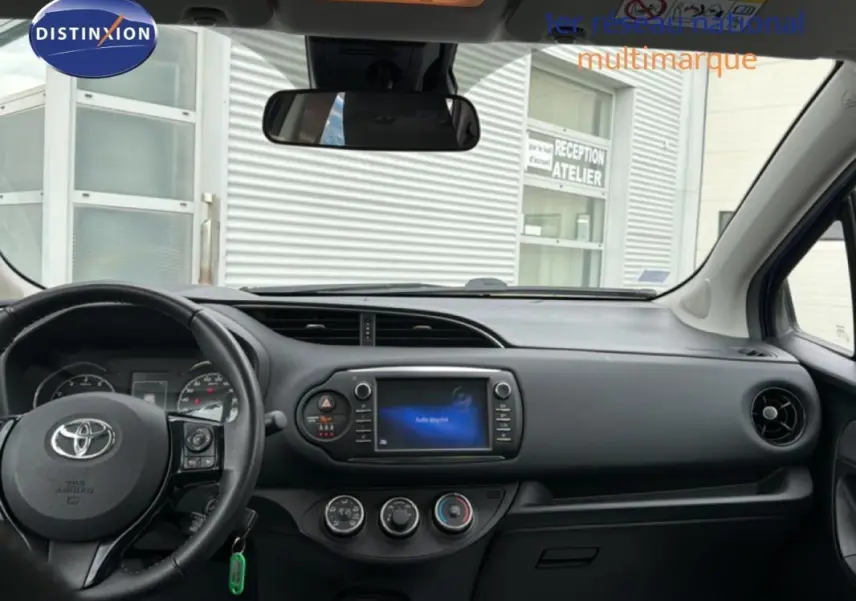 Vue intérieure avant de la Toyota Yaris MC2 69 VVT-i Design 2018, tableau de bord avec écran tactile et volant multifonctions noir.