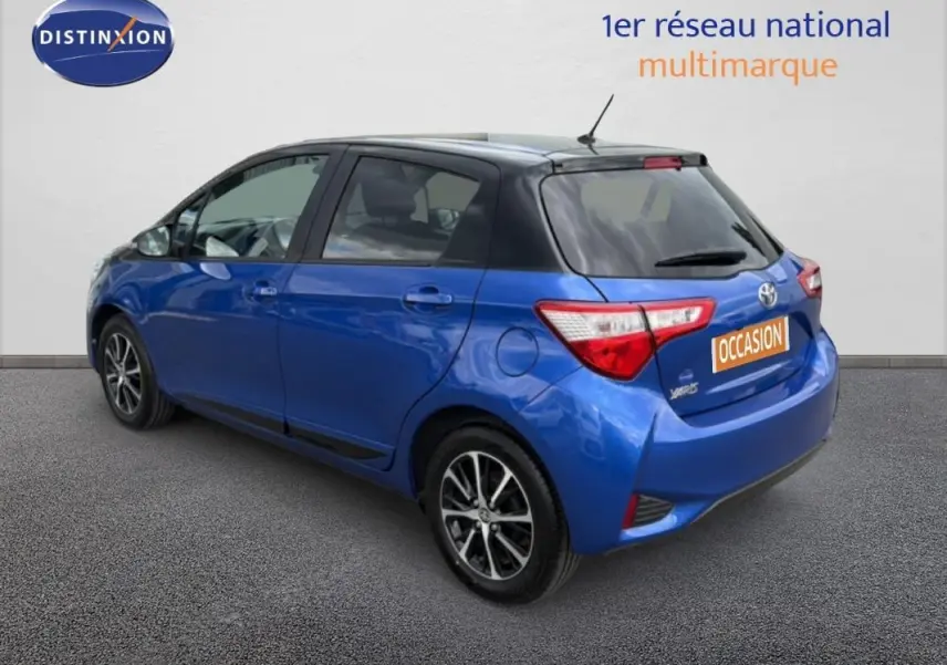Vue 3/4 arrière droite d'une Toyota Yaris bleu foncé avec jantes alliage et feux arrière distinctifs.