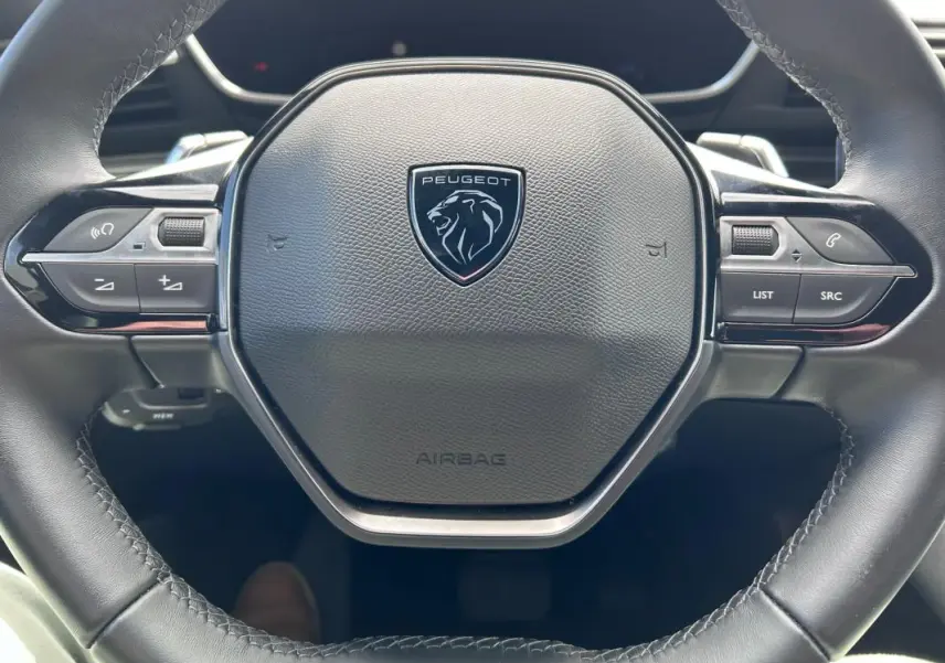 Vue rapprochée du volant cuir noir de la Peugeot 508 Hybrid 225 e-EAT8 avec commandes intégrées.