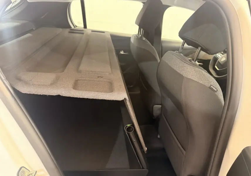 Vue intérieure côté droit de la Peugeot 208 blanche 2025, montrant les sièges avant et la banquette arrière rabattue.