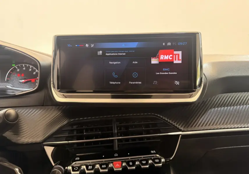 Vue intérieure centrée sur l'écran tactile 7 pouces et la console centrale au design carbone du Peugeot 208 blanc 2025.