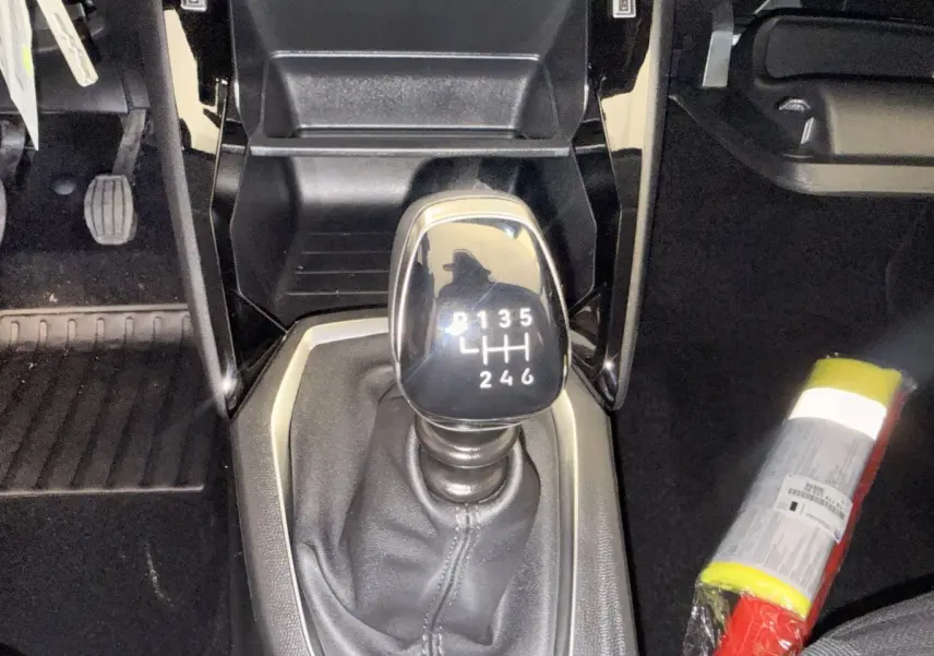 Gros plan sur le levier de vitesse manuel noir de la Peugeot 208, entouré de la console centrale noire et tapis de sol.