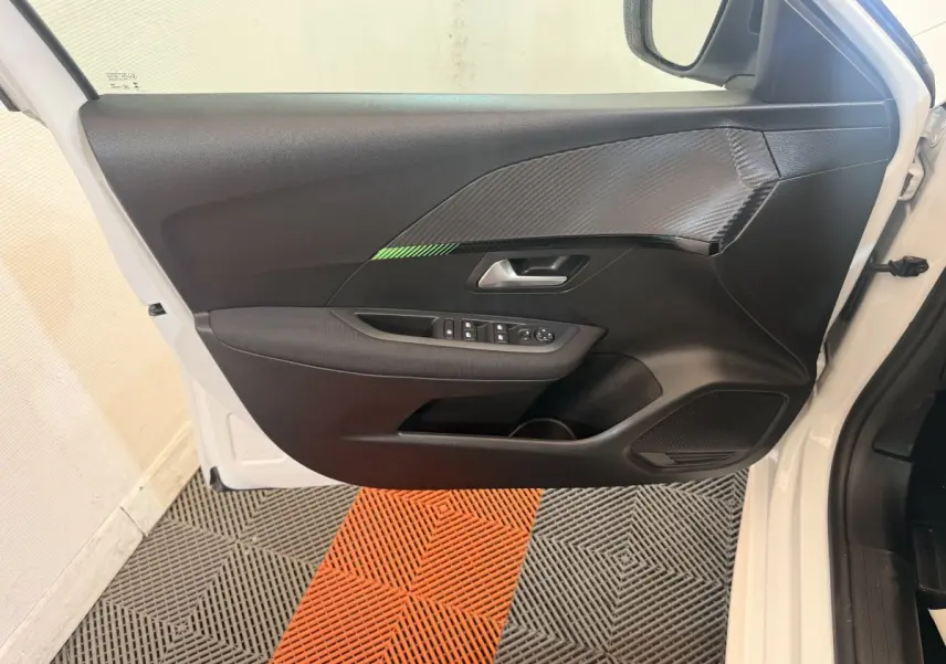 Vue intérieure de la porte avant gauche blanche de la Peugeot 208 2025 avec garniture noire et insert effet carbone.