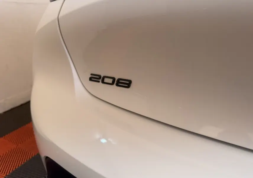 Gros plan sur l'arrière gauche blanc d'une Peugeot 208 avec le logo 208 visible sur le coffre.