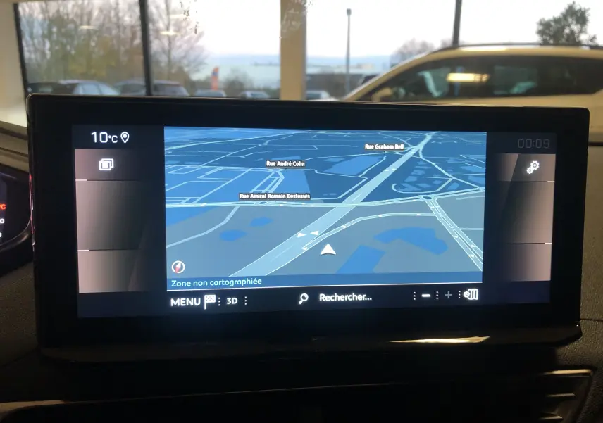 Écran tactile du système de navigation 3D du Peugeot 3008 1.2i 130 GT, intérieur avec vue sur l'extérieur floue.