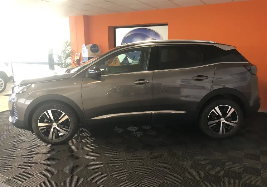 Peugeot 3008 1.2i 130 GT gris platinium avec toit noir, vue de profil côté gauche en intérieur showroom.
