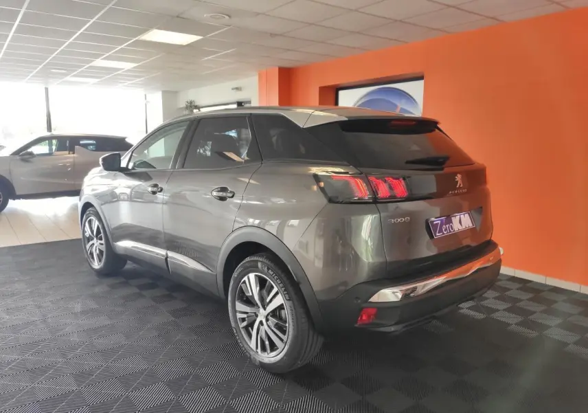 Vue 3/4 arrière droite du Peugeot 3008 gris platinium avec toit noir et jantes bi-ton diamantées dans un showroom.