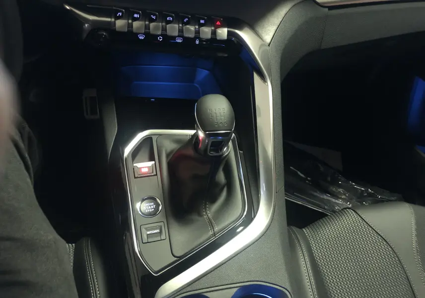 Gros plan sur la console centrale du Peugeot 3008 1.2i 130 GT 2022, avec levier de vitesse manuel et boutons de démarrage et mode sport.