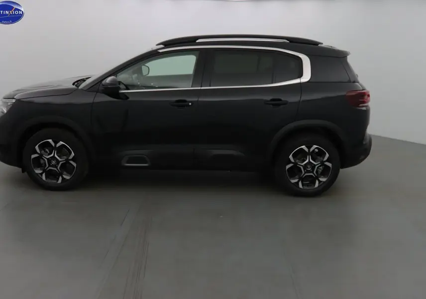 Profil côté gauche du Citroën C5 Aircross noir perle 2022 avec jantes biton et barres de toit visibles.