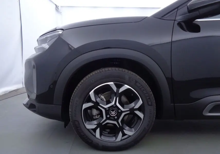 Gros plan sur la roue avant gauche et l'aile d'un Citroën C5 Aircross noir perle, soulignant la jante biton distinctive.