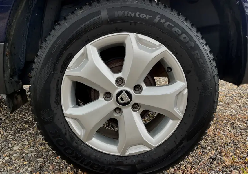 Gros plan sur la roue avant gauche d'un Dacia Duster bleu marine 2018 avec jante alliage et pneu hiver Hankook.