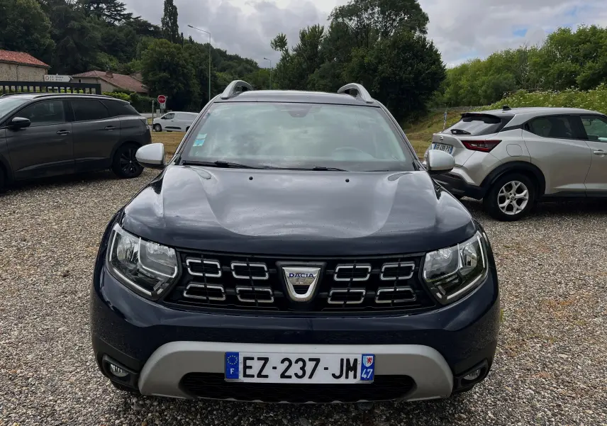Vue frontale d'un Dacia Duster bleu marine 2018 avec calandre noire et plaques d'immatriculation françaises visibles.