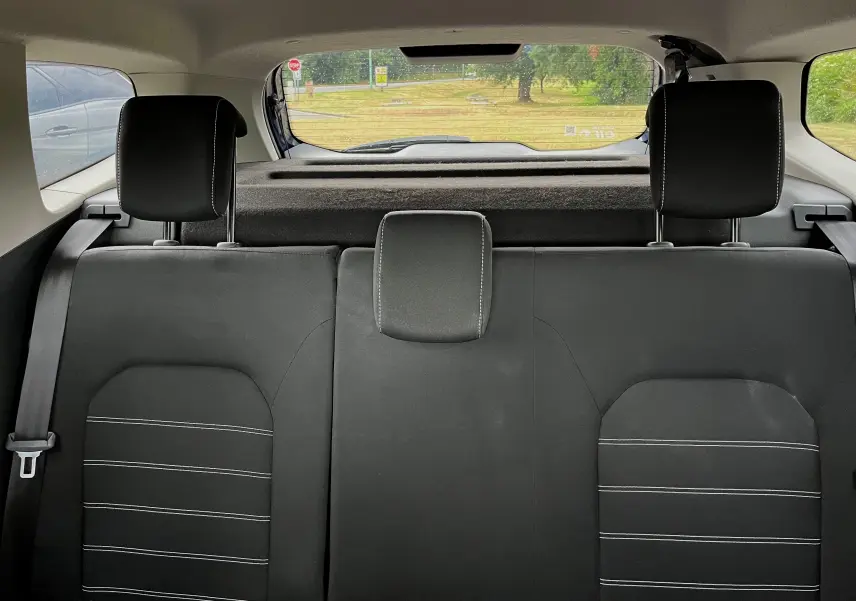 Vue intérieure arrière du Dacia Duster 1.5 DCI 2018 bleu marine, montrant les sièges arrière noirs avec surpiqûres blanches.