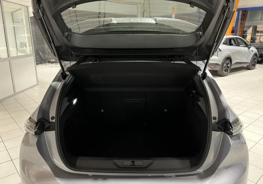 Coffre ouvert vu de l'arrière d'une Peugeot 308 gris Artense en showroom avec feux arrière LED visibles.