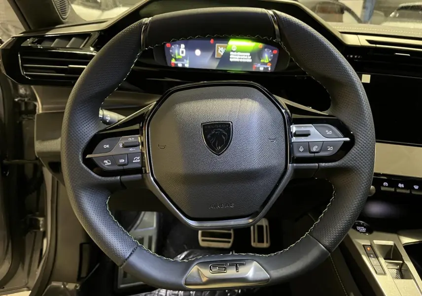 Volant cuir Peugeot 308 GT vu de face avec combiné numérique et pédaliers sport en aluminium visibles