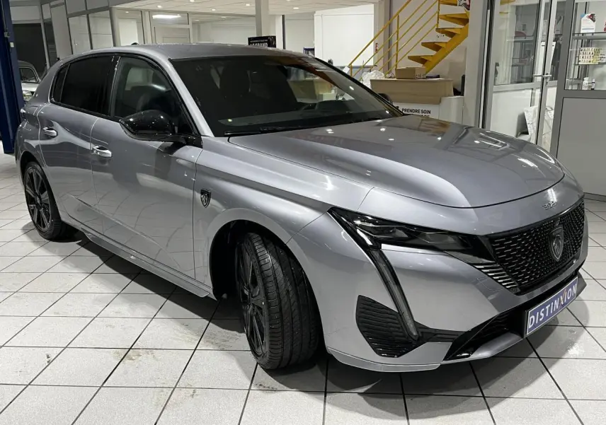 Peugeot 308 gris Artense vue 3/4 avant gauche en intérieur, avec calandre noire et jantes alliage 18'' Kamakura.