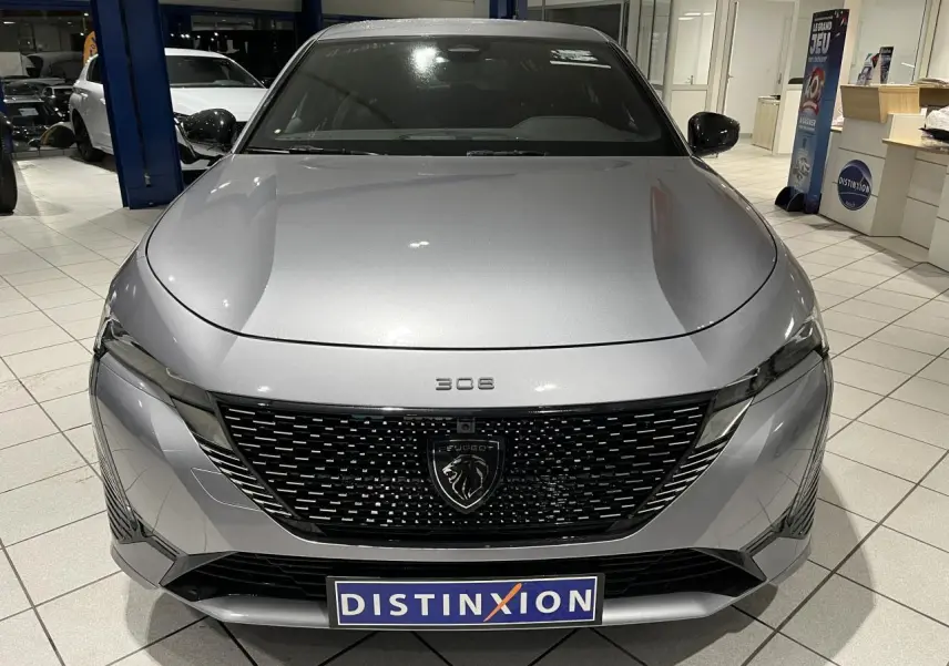 Vue avant d'une Peugeot 308 gris Artense avec calandre noire brillante et badge lion au centre.