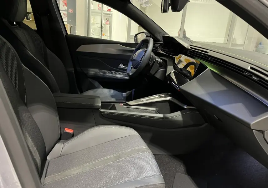 Intérieur avant droit de la Peugeot 308 GT 2024 avec sellerie tissu/TEP gris et planche de bord moderne noire.