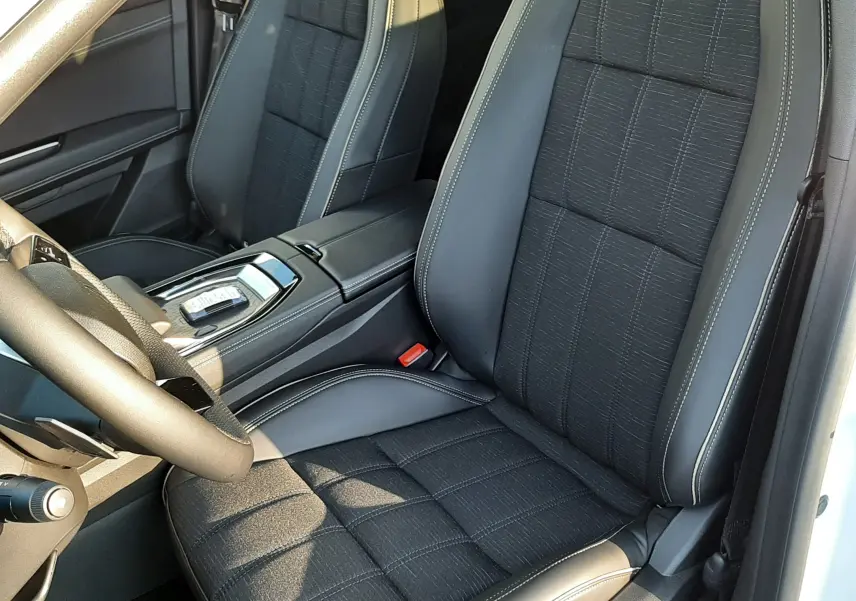 Vue intérieure côté conducteur du Renault Austral E-Tech 2025, sièges noirs en tissu et cuir avec surpiqûres claires.