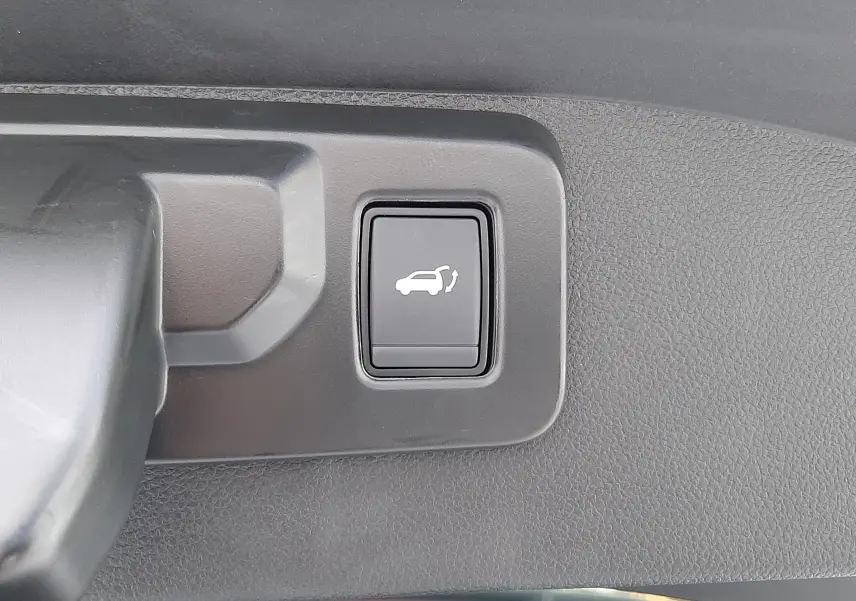 Bouton d'ouverture électrique du hayon sur le coffre intérieur d'un Renault Austral blanc nacré toit noir 2025.