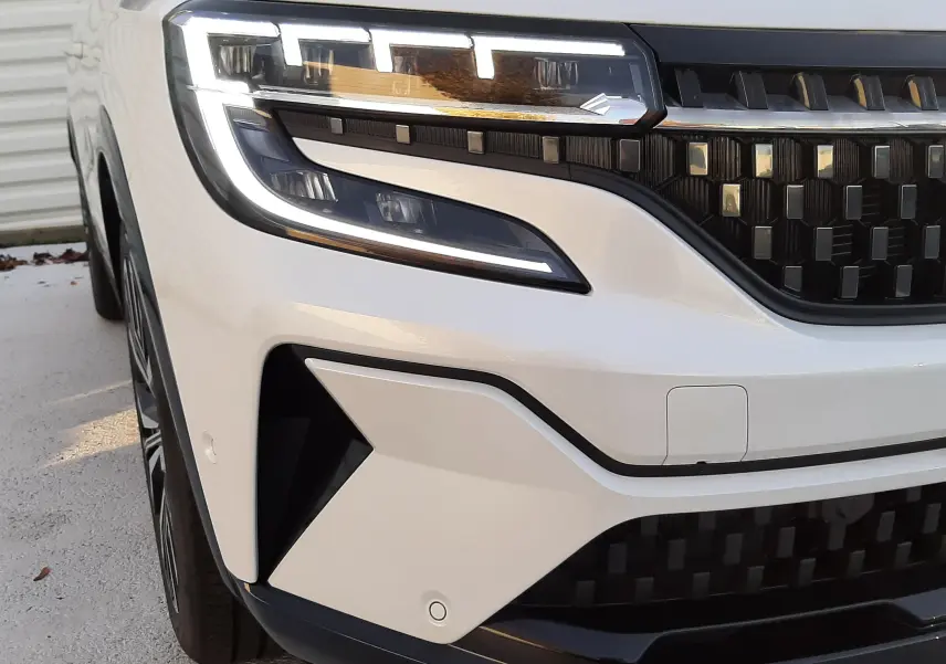 Vue arrière ouverte du coffre d'un Renault Austral 2025 blanc nacré avec toit noir, montrant l'espace de chargement vide.