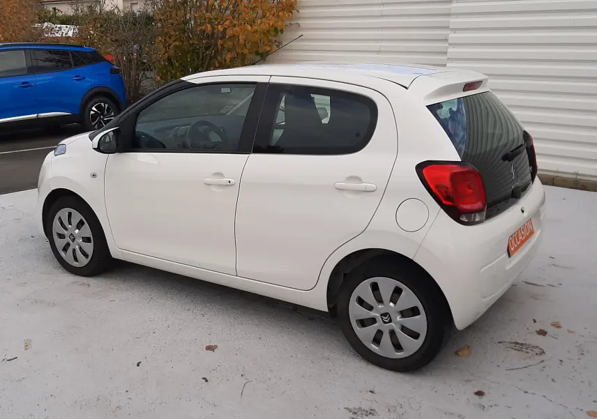 Citroën C1 blanc vue 3/4 arrière côté droit, compacte 5 portes avec feux arrière rouges et jantes acier.