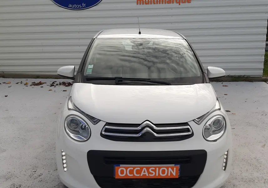 Vue frontale d'une Citroën C1 blanche 2021 avec feux diurnes LED allumés et plaque "OCCASION" visible.