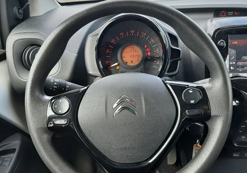 Vue rapprochée du volant noir de la Citroën C1 2021 avec tableau de bord et compteur digital affichant 49295 km.