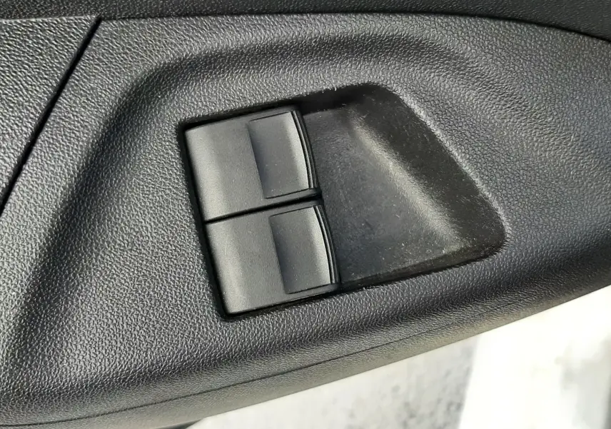 Gros plan sur les commandes de lève-vitres noirs intégrées dans la garniture intérieure noire d'une Citroën C1 blanche 2021.