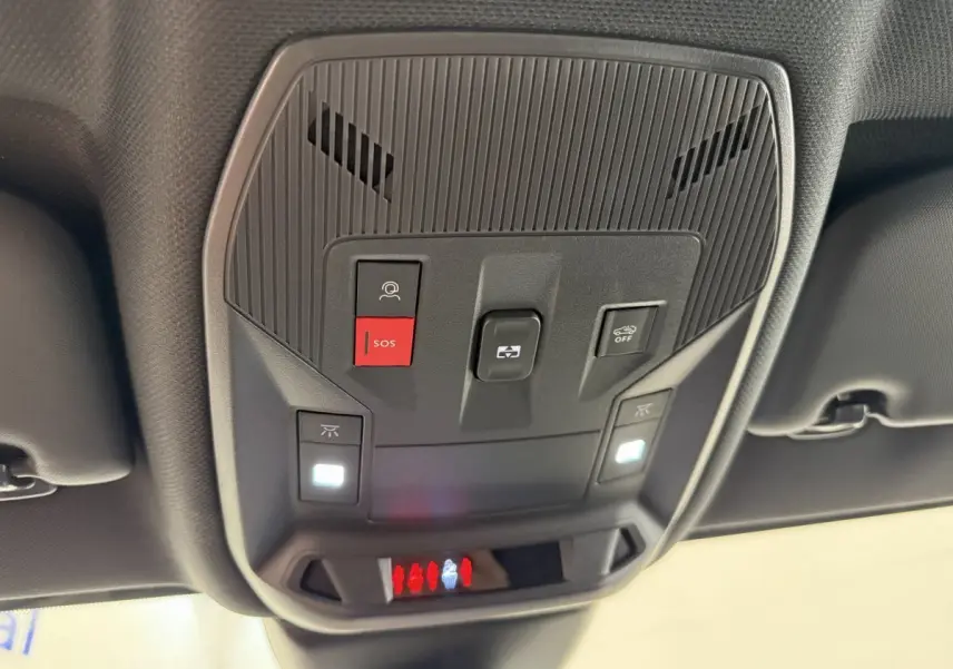 Vue en contre-plongée du panneau de commandes au plafond intérieur noir du Peugeot 308 Hybrid 136 e-DCS6 GT, avec bouton SOS rouge allumé.