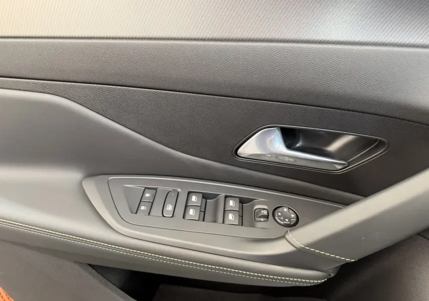 Détail de la porte côté gauche de la Peugeot 308 Hybrid 136 e-DCS6 GT 2024 avec commandes de vitres et poignée argentée.