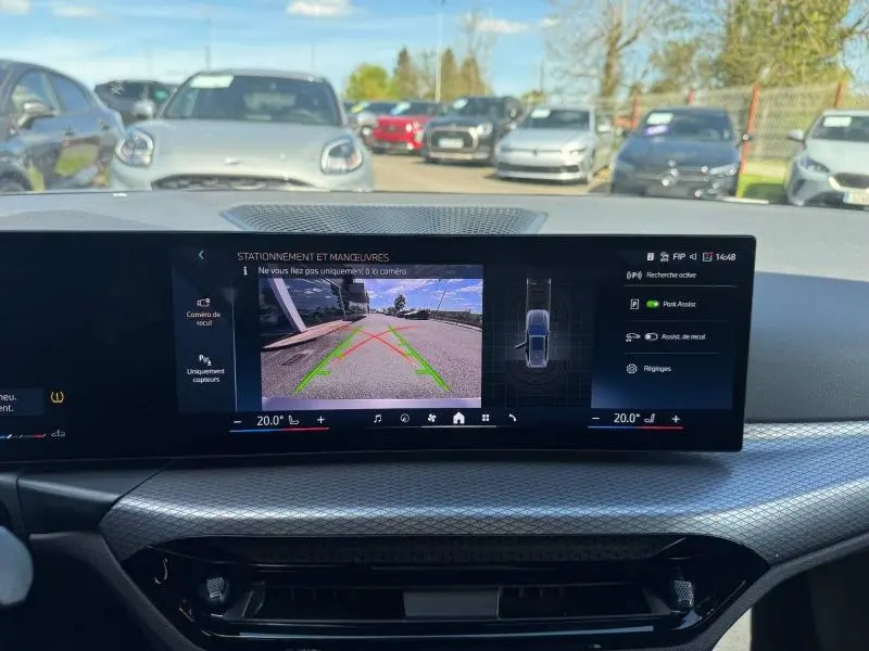 Vue intérieure du tableau de bord de la BMW Série 3 320dA xDrive M Sport 2025 avec affichage caméra de recul et aides au stationnement.