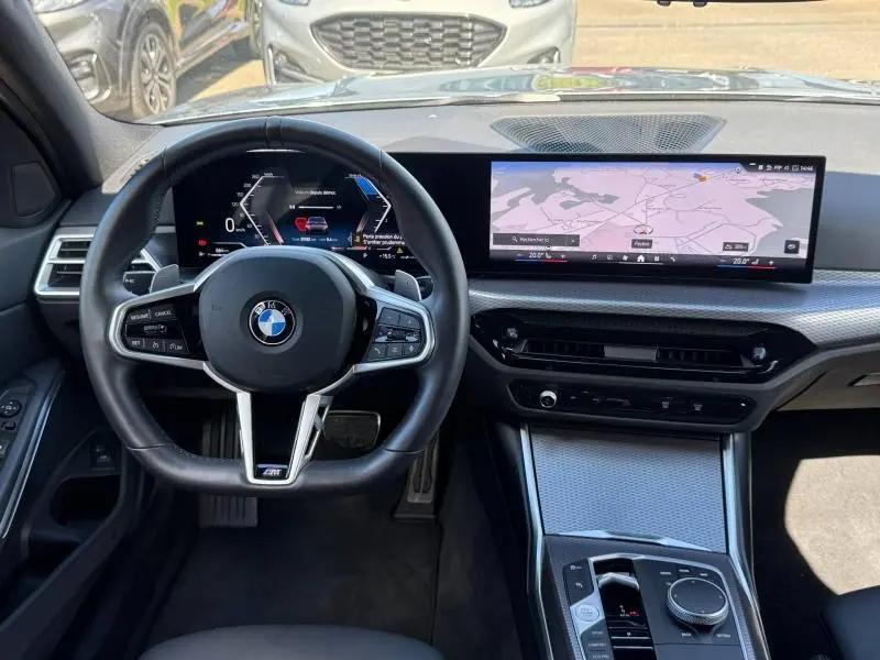 Vue intérieure avant du tableau de bord et volant BMW Série 3 320dA xDrive M Sport avec écran large et finitions carbone.