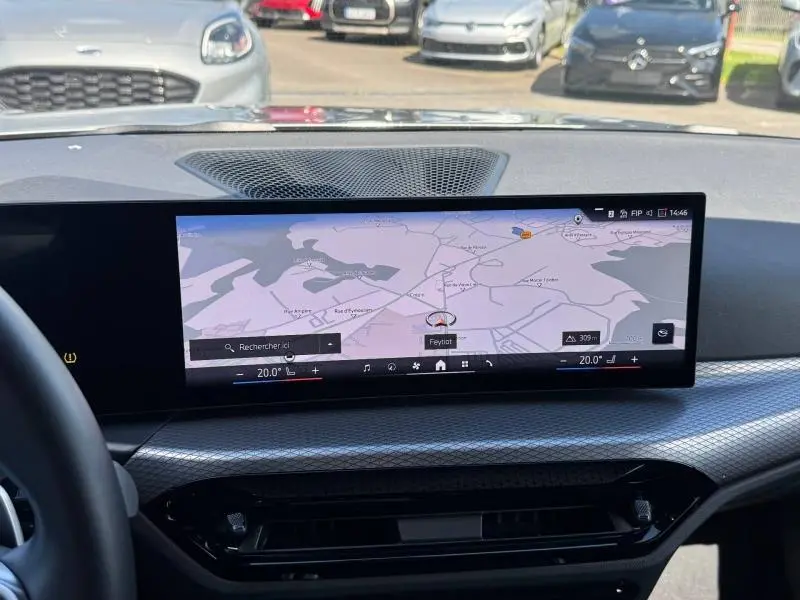 Vue intérieure centrée sur l'écran tactile du tableau de bord de la BMW Série 3 320dA xDrive M Sport 2025, avec navigation affichée.