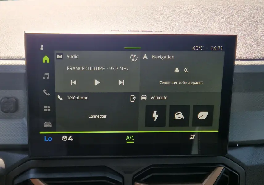 Écran tactile central du tableau de bord du Dacia Duster 1.8 Hybrid 155, affichant radio et options connectivité.