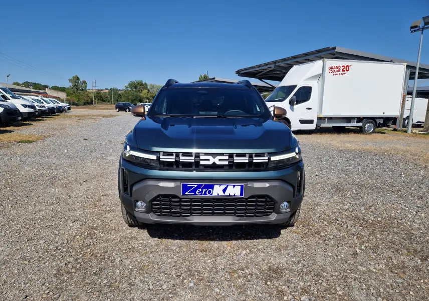 Vue frontale d'un Dacia Duster 1.8 Hybrid 155 Extreme vert cèdre, avec calandre moderne et plaques "Zéro KM".