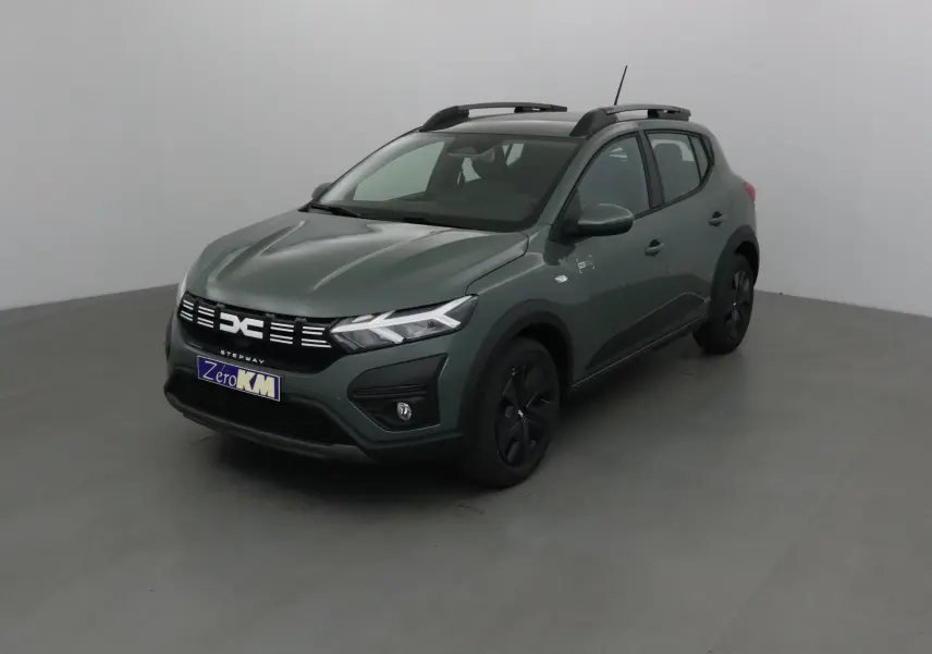 Vue 3/4 avant droite d'une Dacia Sandero Stepway 2025 kaki avec barres de toit et jantes noires.