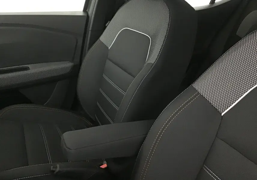 Vue rapprochée des sièges avant noirs avec surpiqûres blanches et accoudoir central dans une Dacia Sandero Stepway 2025.