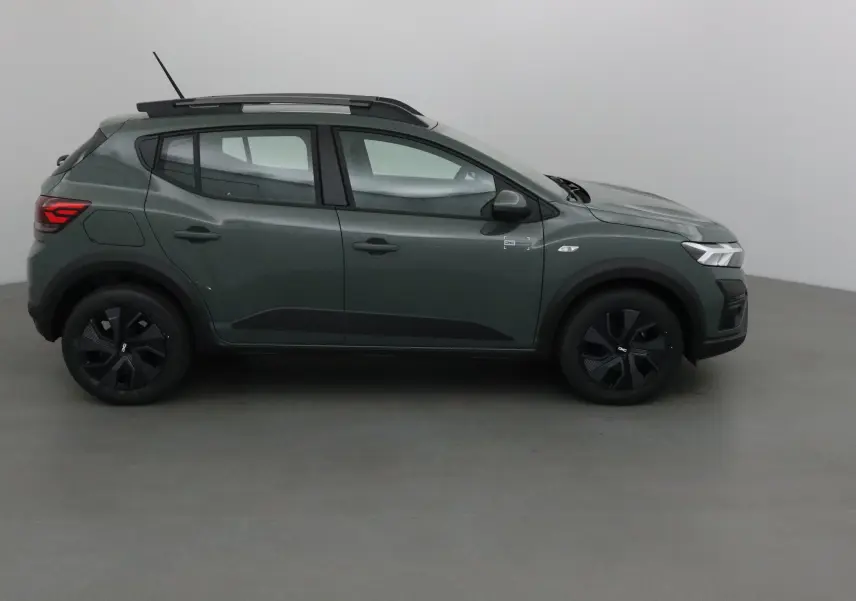 Profil côté gauche d'une Dacia Sandero Stepway 2025 en kaki Kichen avec barres de toit et protections noires.