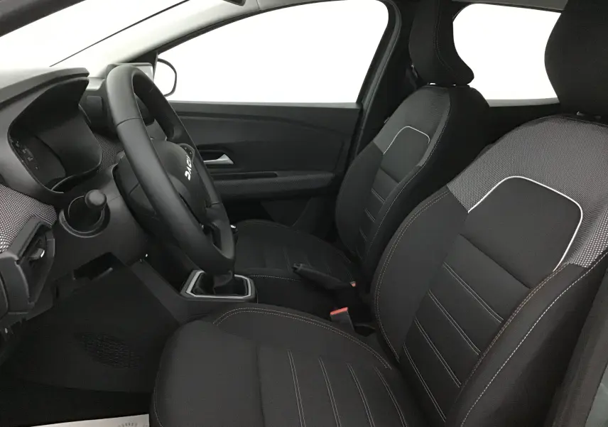 Vue intérieure côté conducteur de la Dacia Sandero Stepway 2025, sièges noirs avec surpiqûres blanches et volant multifonction.