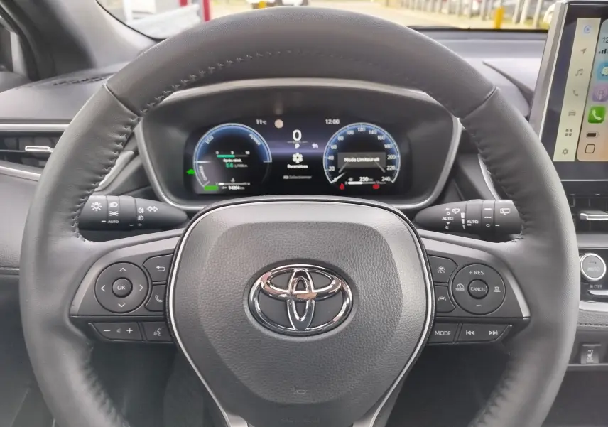 Vue rapprochée du volant noir et du tableau de bord numérique d'une Toyota Corolla Cross 2025 hybride.