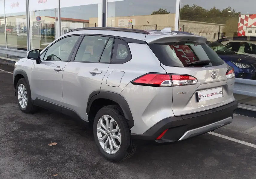 Vue 3/4 arrière droite d'un Toyota Corolla Cross gris acier 2025, avec jantes alliage et feux arrière LED distinctifs.
