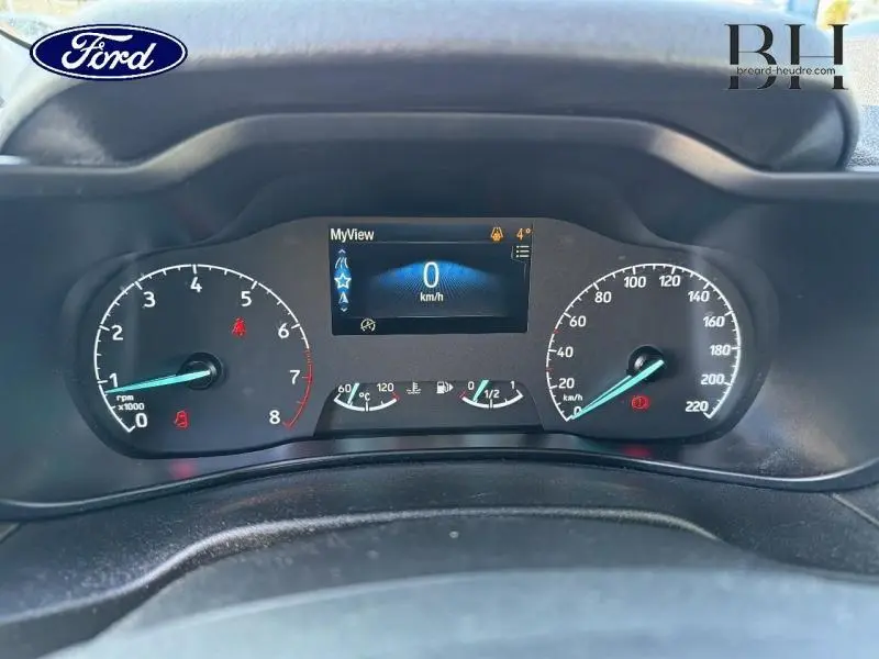 Vue rapprochée du tableau de bord du Ford Transit Connect blanc glacier, affichant le compteur et l'écran digital au centre.