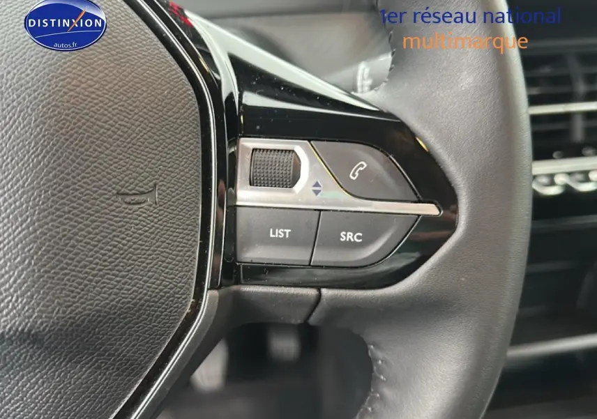 Gros plan sur les commandes au volant noir du Peugeot 208 1.2 PureTech 100 Active 2024, côté gauche.