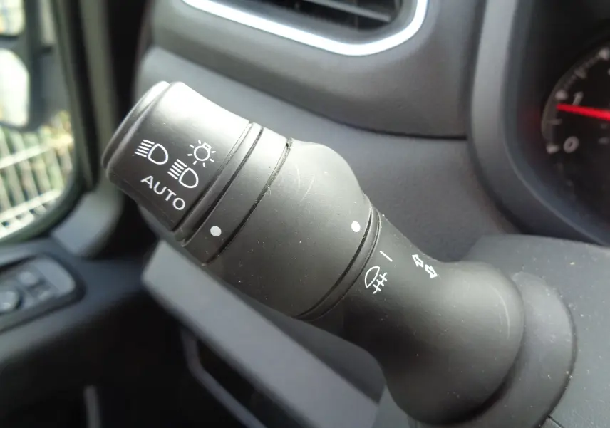 Gros plan sur la manette de commande des phares à gauche du tableau de bord du fourgon Opel Movano blanc polaire.