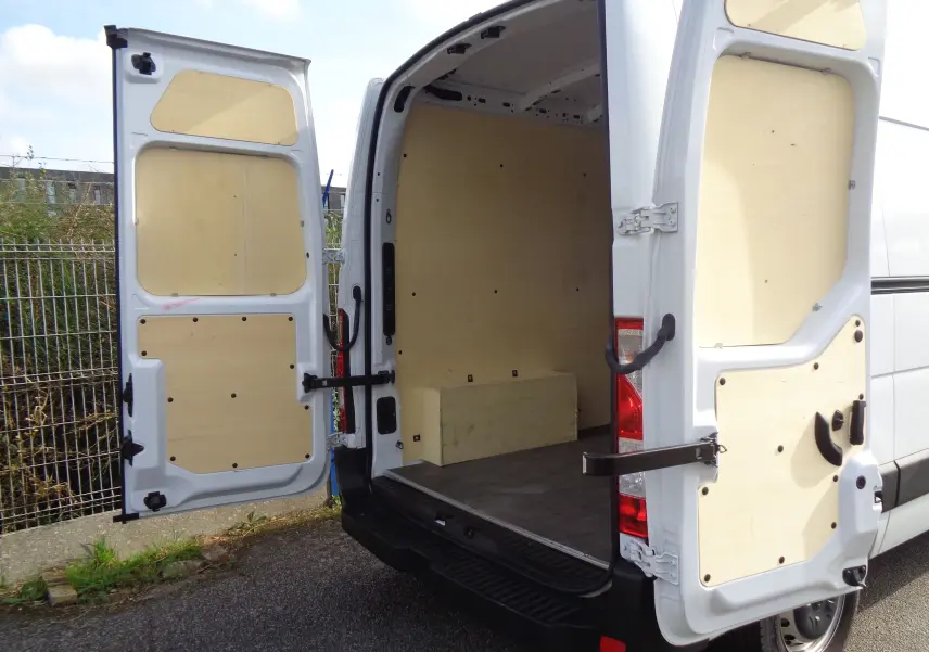 Vue arrière du fourgon Opel Movano blanc polaire avec portes ouvertes montrant l'intérieur vide et panneaux en bois.