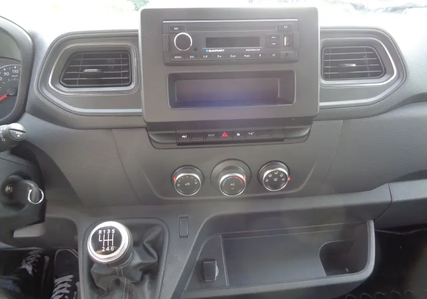 Tableau de bord noir de l'Opel Movano Fourgon 2022 avec commandes manuelles de climatisation et levier de vitesses à six rapports.