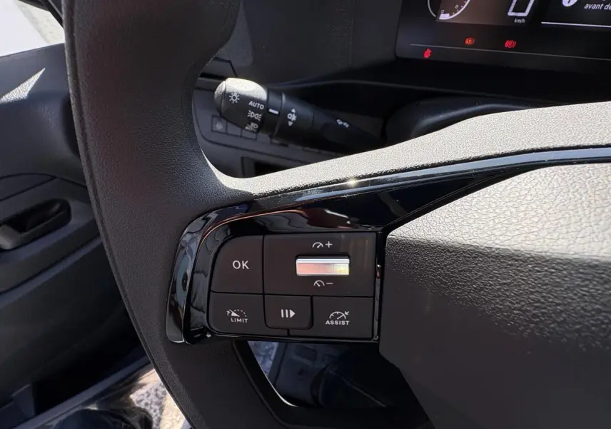 Gros plan sur les commandes au volant à gauche de l'Opel Vivaro blanc 2024, avec boutons de régulateur et assistance.