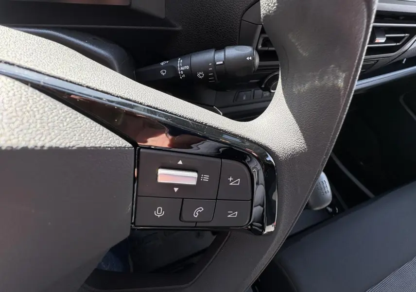 Gros plan sur les commandes au volant gris du poste de conduite de l'Opel Vivaro blanc 2024 avec boîte manuelle.