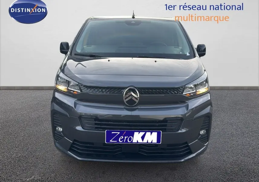 Vue frontale d'un Citroën Jumpy Fourgon XL gris titane métal avec phares allumés sur fond neutre.